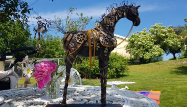 Hästskulptur med nycklar och hänglås som står på ett bord i solskenet