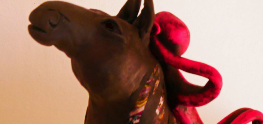 Skulptur med liten figur som vilar på en hästrygg