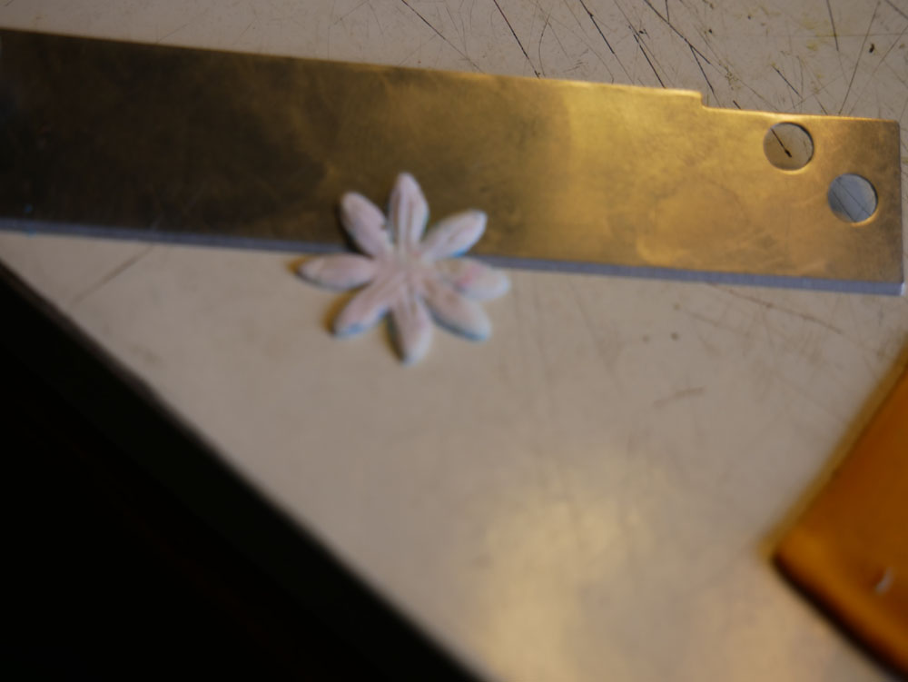 a white polymer clay flower and a cutting blade