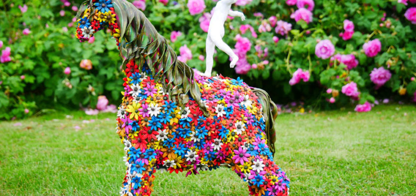Horse sculpture covered on flowers, with a man standing on its back