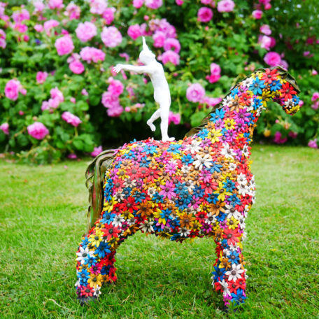 Horse sculpture covered on flowers, with a man standing on its back