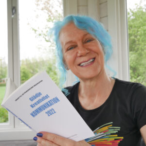 Porträttbild av EvaMarie Törnström som håller i sin bok Glädje Kreativitet Kommunikation 2022